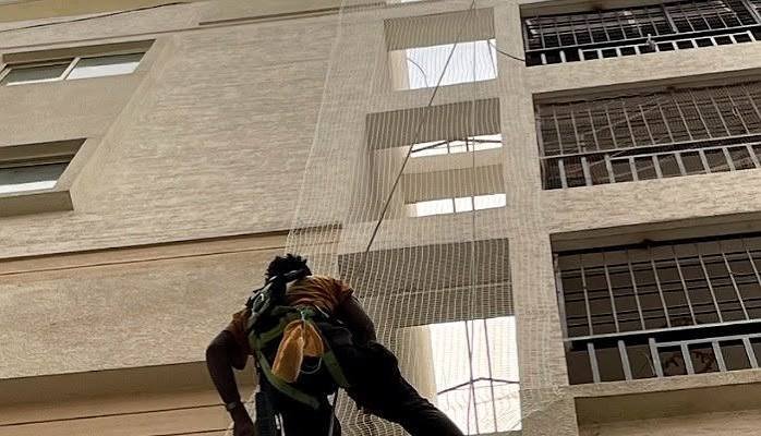 Technician installing a safety net on a building exterior
